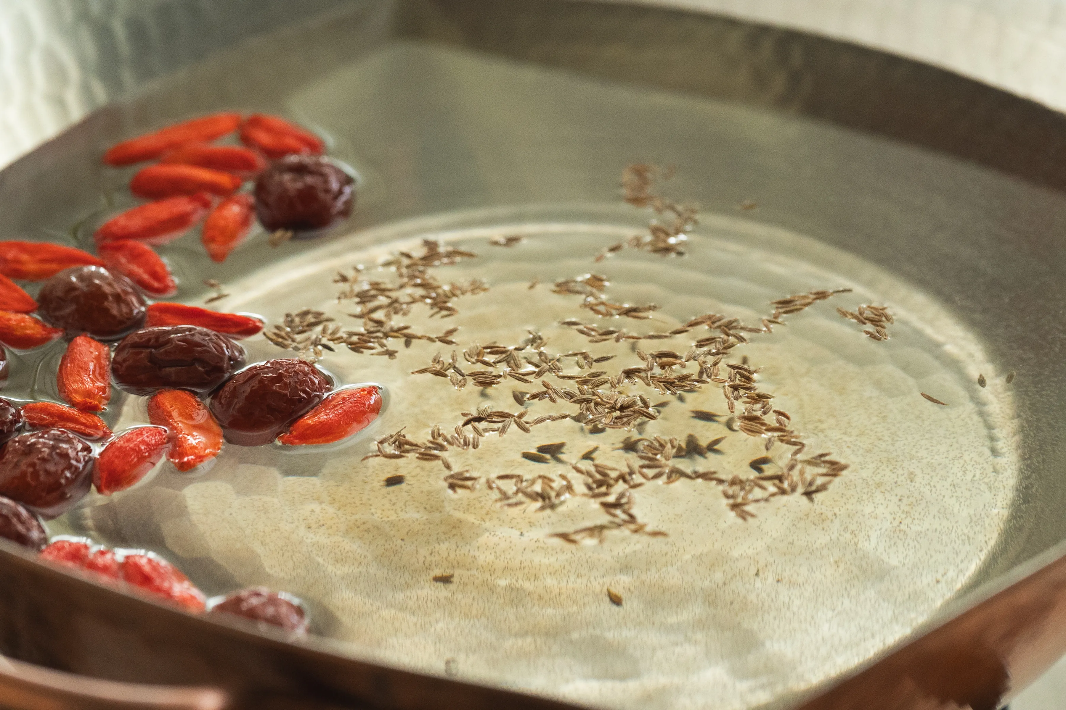 鍋にクミンやクコの実を入れる様子